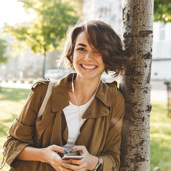Laser Dentistry Woman with Phone Smiling by Tree